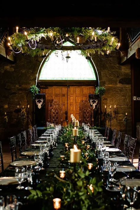 Picture of a LOTR wedding reception space indoors, with a black table with greenery and gold candles, a greenery chandelier with vines Elven Wedding Reception, Viking Wedding Table Centerpieces, Game Of Thrones Wedding Aesthetic, Medieval Centerpieces Wedding, Celtic Woodland Wedding, Fantasy Wedding Ceremony, Midevil Wedding Theme Ideas, Dark Boho Wedding Color Schemes, Dragon Age Wedding