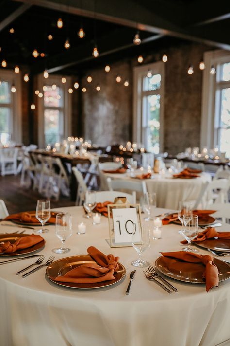 Fall Wedding Reception Table Decor with Rust Silk Napkins and White Linens | Edison Bulb Lighting Fall Color Wedding Table Decor, Fall Wedding Table Linen Ideas, Round Table Wedding Decor Burnt Orange, Rust Orange Table Setting, Rust Wedding Ceremony Decor, Chic Fall Wedding Decor, Subtle Fall Wedding Decor, Fall Wedding Table Linens, Fall Wedding Round Tables