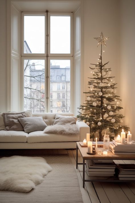 This minimalistic nordic holiday decoration fits a simple taste. The early 1900s apartment with large windows and wooden floors create a perfect setting for the white sofa with big pillows, white rug and fur on the floor, wooden coffee table with black metal frame, candles and medium sized christmas tree with elegant white decorations and lights. Minimalist Modern Christmas Tree, Simple Scandinavian Christmas, Nordic Christmas Tree Ideas, Scandinavian Christmas Living Room, Christmas Hygge Aesthetic, Minimalist Christmas Table Setting, Christmas Tree Modern Minimalist, 1900s Apartment, Christmas Tree Scandinavian Style