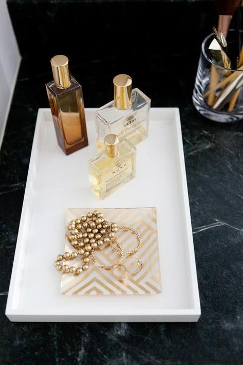 A soapstone vanity top is lined with a white lacquer vanity tray from West Elm lined with gold perfumes and a gold chevron jewelry tray. Soapstone Vanity, Bathroom Tray Ideas, Bathroom Tray Decor, Perfume Versace, Bathroom Vanity Tray, Bathroom Counter Decor, Jewerly Organizer, Chevron Jewelry, Decor Pad