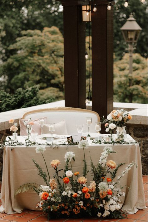 The sweetheart table with Italian ruscus runner, bud vases and a ground arrangement in front. This peach and orange palette was perfect for a summer garden wedding. Sweetheart Floral Arrangement, Front Table Decor Wedding, Spring Sweetheart Table Wedding, Sweetheart Table Ground Flowers, Wedding Floral Centrepiece, Wedding Decor Sweetheart Table, Summer Wedding Sweetheart Table, Wild Flower Sweetheart Table, Sweetheart Table With Bud Vases