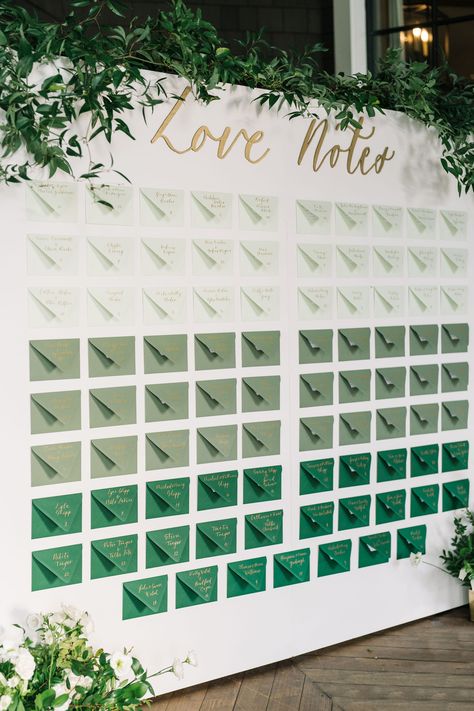 A green seating chart for wedding reception with greenery and flowers surrounding it. Perfect for a wedding that has green in their color palette. The couple wrote a note to each guest. Wedding Seating Assignment Display, Creative Table Seating Chart Wedding, Matches Seating Chart, Emerald Seating Chart, Golf Course Seating Chart, Big Wedding Seating Chart, Wedding Favors Seating Chart, Reception Seating Chart Layout, Thank You Note Seating Chart