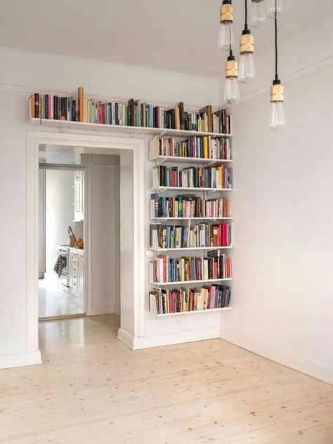 bookshelves covering one wall next to the doorway and a space over it will give you much space for books and will help you declutter the space Book Shelf Over Doorway, Above Doorway Shelf, Built In Over Doorway, Over Doorway Bookshelves, Bookcase Over Door, Shelving Above Doorway, Shelving Around Doorway, Above Door Bookshelf, Bookshelf Around Doorway