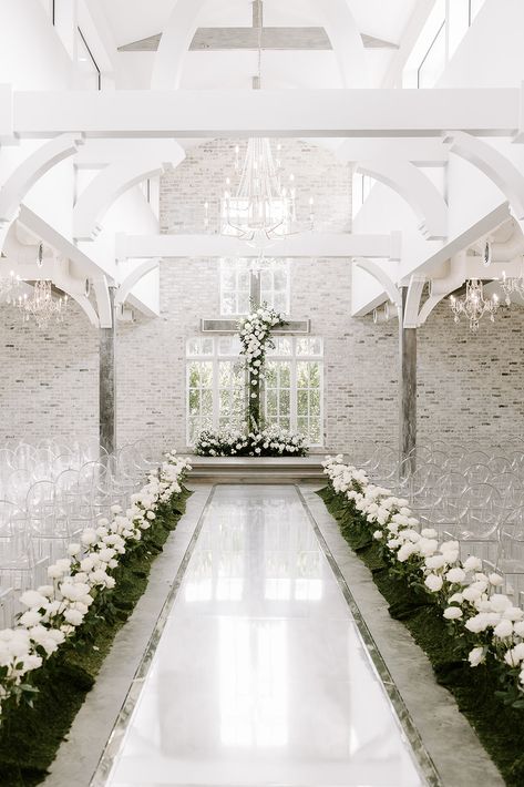 A modern and elegant wedding ceremony with all white florals and accenting greenery installed on and placed in front of the alter cross and long stemmed white roses lining the aisle as if growing up from the ground | Florals: Cali & Bloom, Venue: The Peach Orchard, Planning: Jolie Planning and Design, Photography: Erika Geier Photography Cross Aisle Wedding, White Cross Wedding Alter, White Roses Wedding Ceremony, White Rose Aisle Wedding, The Peach Orchard Wedding, Cross Alters For Weddings, Wedding Aisle Indoor, Wedding Esthetics, Orchard Planning