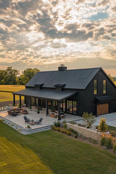 High angle view of a large black shouse barndominium with large side porch large patio and yard stone patio fence large garage doors wide. Unlock the secrets of shouse barndominiums and find out how you can live where the wild west meets modern luxury. Large Property Ideas, Barndo Patio Ideas, Barndominium In Mountains, Dream Barndominium Ideas, House Shop Design, Compound Ideas Home, Barndominium Front Entrance, Barndominium Home Plans, Black Barndominium Exterior With Stone