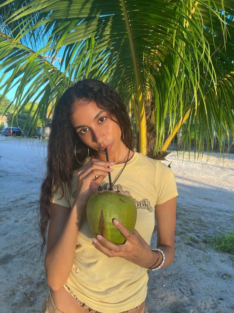 Coconut, coconut trees, island girl, island vibes, island aesthetic, coconut girl, waist beads, island outfit, wavy hair, natural makeup, relaxing vibes, aesthetic pic, tan, palm trees, sand, beachy vibes, beach, yellow tee, y2k graphic tee, drinking coconut Aesthetic Coconut Girl, Aesthetic Coconut, Island Aesthetic, Barbie Summer, Island Outfit, Coconut Trees, Beachy Vibes, Waist Beads, Coconut Girl