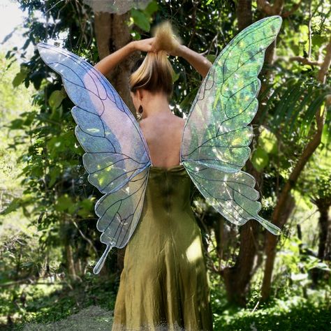 Woman with her back facing the camera, wearing iridescent and translucent fairy wings, pulling her hair up. She is standing in the rainforest garden and wearing a vintage green dress. Homemade Fairy Wings Diy, Realistic Fairy Wings Diy, Fall Fairy Wings Diy, Organza Fairy Wings, Wire Fairy Wings Diy, Fairy Pixie Costume, Diy Wire Fairy Wings, Cosplay Fairy Wings Diy, Fairy Wings Fabric