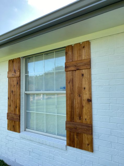 DIY shutters, made with cedar fence pickets, and hellmans clear sealer. Cedar Window Shutters Exterior, Cedar Board And Batten Shutters, White Brick House Cedar Shutters, Rustic Wooden Shutters Exterior, Farmhouse Wooden Shutters, White Brick House With Cedar Shutters, Cedar Shutters On Brick House, Wooden House Shutters, Blue House Cedar Shutters