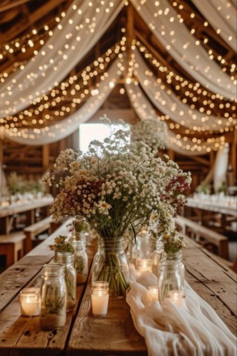 Rustic barn wedding table decoration, fairy lights Fairy Lights Wedding Barn, Rustic Wedding White Flowers, Moody Rustic Fall Wedding, Fairy Garden Reception, Elegant Rustic Wedding Ideas Decorations, Wedding Decor Country Rustic, Wedding Venue Ideas Rustic, Rustic August Wedding, Rustic Farm Wedding Reception