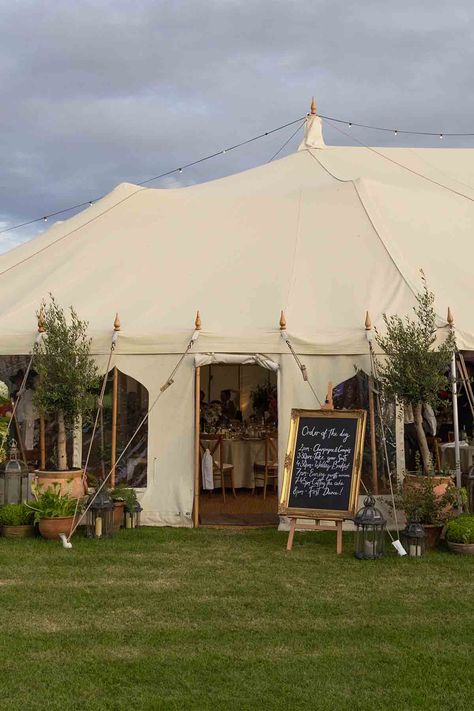 Large marquee wedding with a gold framed order of the day sign, moroccan lanterns from Onkoi and large potted plants and trees that surround the entrance of the marquee at a outdoor wedding in the Cotswolds, UK. The marquee is situated amongst a wild flower garden planted and nurtured by the bridal couple. Small Wedding Marquee, Garden Marquee Party, Backyard Wedding Marquee, Wedding Flowers Marquee, Outdoor Marquee Wedding, Wedding Marquee Flowers, Rustic Nature Wedding, Marquee Wedding Flowers, Small Marquee Wedding