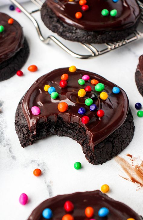 Say hello to this upgraded cookie version of your favorite childhood treat! These Cosmic Brownie Cookies are rich chocolate cookies with a shiny chocolate ganache frosting. They are topped with the traditional cosmic brownie chips, and make for a chocolate lovers heaven! Chocolate Cookies With Ganache, Chocolate Cookies With Frosting, Desserts That Keep At Room Temp, Cosmic Brownie Cupcakes, Chocolate Crumbl Cookies, Cookies With Chocolate Frosting, Fudge Fancy Cookies, Super Yummy Desserts, Munchies Food