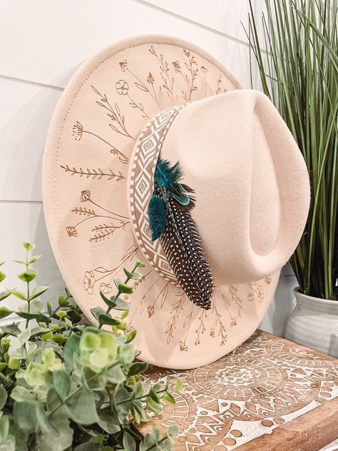 Wildflower Floral Burned Hat, Floral Engraved Cowboy Hat, Sunflower Hat, Sunflower Burned Fedora, Engraved Fedora, Engraved Felt Hat, Boho Hat Elevate your style with our beautifully engraved floral hats! If you want certain colors for the feather/flower detail, please leave a note at checkout. Bands and florals/feathers may shift or fall off during shipping. The hat has an adjustable band on the inside to fit many sizes. One size fits most adult heads. Decorated Felt Cowboy Hats, Custom Burned Felt Hats, Custom Cowboy Hat Ideas, Burned Hat Design, Cowboy Hat With Flowers, Boho Hats For Women, Hat Burning Ideas, Hat Burning Designs, Western Hats For Women