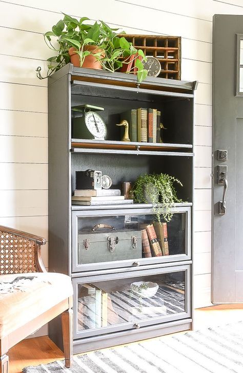 Styled with unique vintage finds, this old oak barrister bookcase gets a fresh modern makeover with Sherwin-Williams Iron Ore.  #furnituremakeovers #barristerbookcase #paintedfurniture #ironore #beforeandafter Bookcase Makeover, Barrister Bookcase, Bookcase Styling, Bookcase Decor, Vintage Farmhouse Decor, Iron Ore, Farmhouse Furniture, Diy Furniture Projects, Furniture Makeover Diy