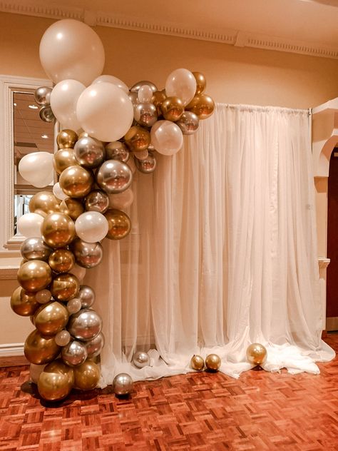 A simple, yet elegant design for a backdrop made from gold/silver/white balloon arch and a white drape backdrop. #eventdecor #balloons #balloonarch #balloondecor #backdrop #drapes #eventrentals Balloon Garland Rectangle Backdrop, Backdrop With Balloons On Side, Wedding Decoration White And Gold, White And Gold Balloon Backdrop, Simple Balloon Arch Backdrop, Elegant Balloon Arch, White And Gold Balloons Decoration, White Drape Backdrop, Simple Balloon Backdrop