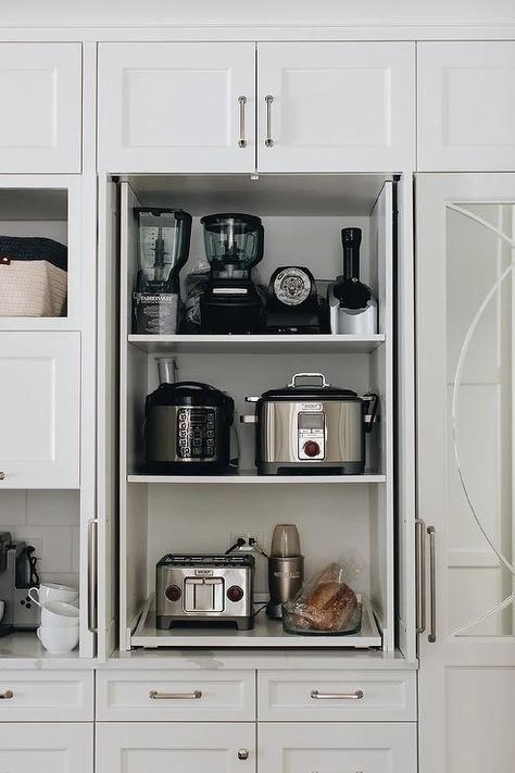 Fitted with pull out shelves, a small appliances cabinet is finished with white doors and nickel hardware and fixed beneath a white over head cabinet. Kitchen Appliances Cabinet, Cabinet With Pull Out Shelves, Appliances Cabinet, White Kitchen Shelves, Gorgeous White Kitchen, Kitchen Appliance Storage, Appliance Cabinet, Blue Kitchen Cabinets, Pull Out Shelves