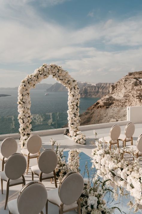 A white sunset micro-wedding with macro luxury details in Santorini White And Off White Wedding, Beach Wedding Candle Aisle, White Rose Walkway Wedding, Oceanfront Wedding Ceremony, Mirrored Isle, Beach Wedding Walkway, Wedding Ceremony Arch Ideas, Timeless Beach Wedding, Destination Wedding Greece