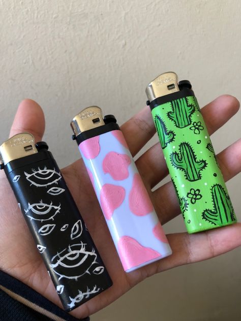 Acrylic paint designs: creepy eyes, pink cow print, cute green cacti Aesthetic Lighter Drawing, Drawing On Lighter Ideas, Painting Lighters Diy, Lighter Ideas Diy, Lighter Art Diy, Painting On Lighter, Painted Lighters Aesthetic, Diy Lighter Painting, Painted Lighter Aesthetic