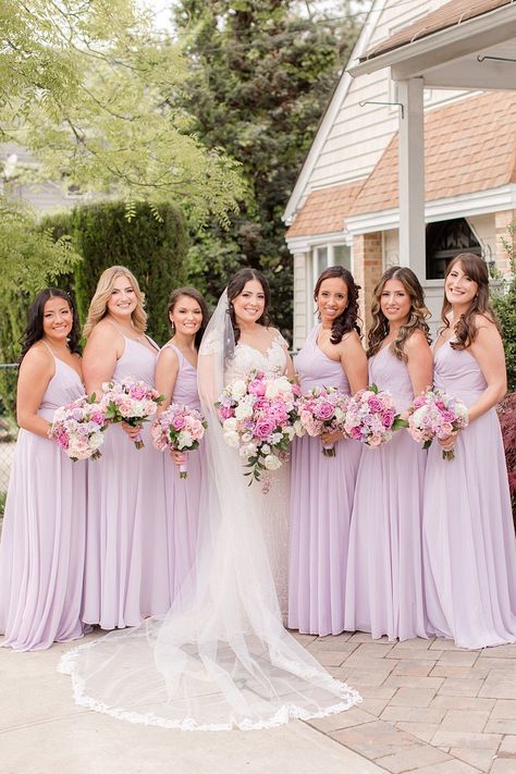 bride poses with bridesmaids in lilac gowns outside home | Spring microwedding inspiration in Staten Island NY photographed by New York wedding photographer Idalia Photography. Planning an intimate microwedding? Find inspiration here! #IdaliaPhotography #NYWedding #StatenIslandWedding #SpringWedding #Microwedding Lilac Pink Bridesmaid Dresses, Wedding Party Color Scheme Spring, Purple Pastel Bridesmaid Dresses, Lilac Bridesmaids, Lilac Satin Bridesmaid Dresses, Lilac And Light Pink Wedding, Pink And Purple Bridesmaid Dresses, Pastel Blue And Purple Bridesmaid Dresses, Lavendar Bridesmaids Dresses