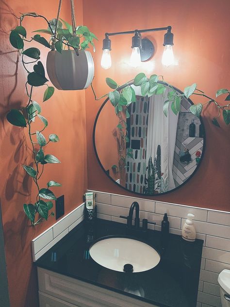 Pothos make for a perfect bathroom plant as long as you have a window. I love how the green contrasts against the terracotta paint. White subway tile and black grout is one of my favorite backsplash combos and I’m obsessed with it. ♥️ Kept it simple with black fixtures. Boho Bathroom Black Countertop, Black And Peach Bathroom, Plants Over Mirror, Green And Orange Bathroom Decor, Small Bathroom With Plants Decor, Green Tiny Bathroom, Terracotta Painted Bathroom, Electric Bathroom Decor, Terracotta And Black Bathroom