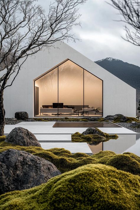 Modern minimalist symmetrical white concrete house facade with glass walls front yard with mossy rocks Japanese mountains in the background. Check out how these stunning modern houses create peaceful and strikingly Zen havens with their tranquil exterior designs. Japanese Minimalist Home Exterior, White A Frame House Exterior, Japan Home Exterior, Nordic House Design Exterior, Japanese Style Architecture, Japanese Modern Architecture, Japanese Zen House, Modern Glass House Exterior, Wood And Concrete Architecture