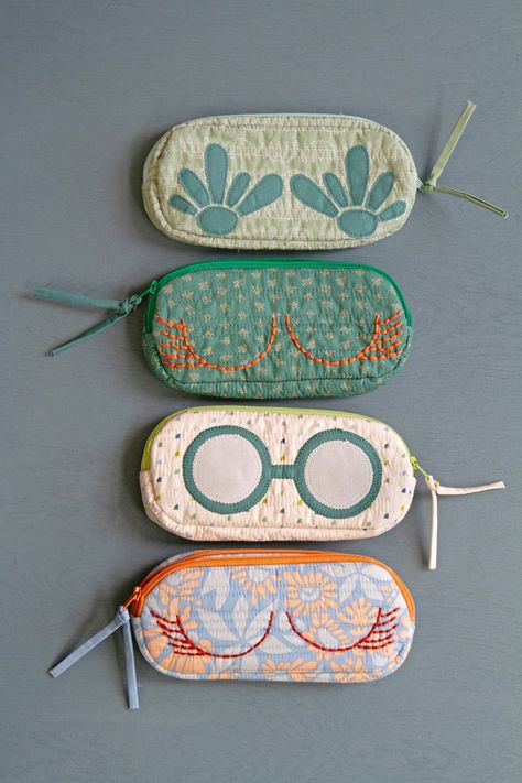 These charming handmade sunglasses cases are more than just protection; they're mini works of art featuring prints from the Suzy Quilts Evolve Collection!  Hand-stitched details elevate them to pure inspiration! Dive into our Evolve Lookbook for more creative sparks! #ArtGalleryFabrics #AGFEvolve #QuiltingCotton FabricCrafts #DIYProjects #Sewing #DIYHandmade #SmallSewingProjects #TextileProjects #HandSewing #Embroidery #CuteDIY #Quilting #SewingProjects #SpringCrafts #SummerCrafts #DIYPouches Sunglasses Cases To Sew, Sew Useful Things, Sew Sunglasses Case, Quilted Sunglasses Case, Cute Sewn Gifts, Seeing Gifts, Fabric Glasses Case, Fashion Gifts Ideas, Sew Travel Accessories