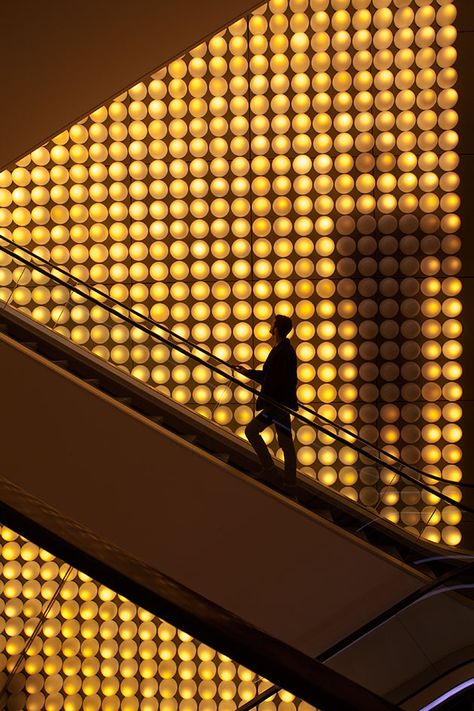 At first, it might seem counterintuitive to discover that a 13-metre creation by Xavier Veilhan has been installed on a wall behind crisscrossing escalators in a department store. Never mind the obstructed view – people in closest proximity to the i... Lafayette Wallpaper, Escalator Lighting, Light Bulb Wall, Wall Of Light, Lighting Installation, Lighting Art, Mall Design, Glass Brick, Kunming