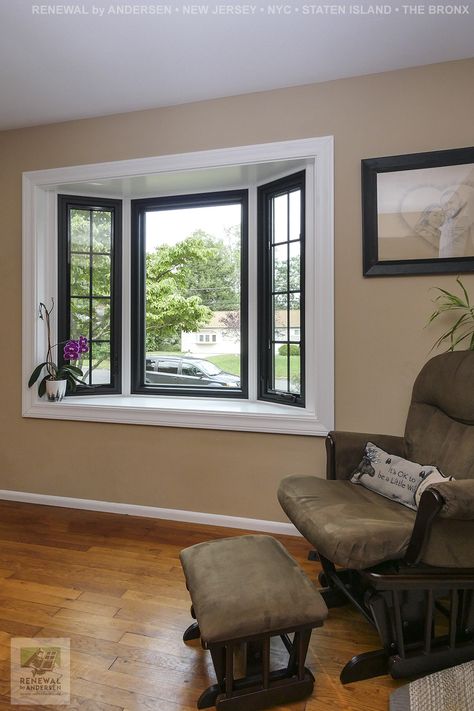 Beautiful new bay window, with white frame and black windows, that we installed in this charming sitting area. This bay window is made up of three windows, a large picture window in the middle and two smaller casement windows with grilles on either side. Find out more about getting new windows in your home from Renewal by Andersen of New Jersey, New York City, Staten Island and The Bronx. Painted Bay Windows Interior, Picture Window Replacement Ideas, Bay Window Replacement Ideas, Modern Bay Window Exterior, Bay Window Exterior Ideas, Black Bay Window, Picture Window Ideas, Picture Windows Exterior, Diy Bay Window