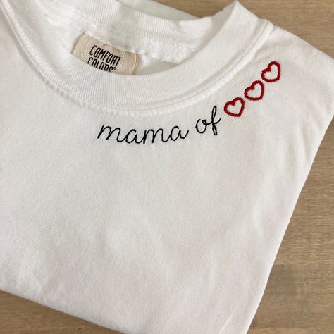 "My absolute favorite tee! This custom tee can be customized to your preferred thread color and is stitched on a Comfort Colors short sleeve unisex tee. \"Mama of\" will be stitched along the collar along with the number of hearts to represent each child! For shirts that require more hearts, they may need to be stitched on multiple lines.  Please wash on gentle cycle and dry on low.  If you are wanting a different design, wording, or a different clothing style, please send me a message so we can discuss the details. Please include thread color at checkout If you need this order rushed, please add these to your cart: https://www.etsy.com/listing/1043569716/rush-my-order-for-t-shirts?ref=shop_home_active_19&frs=1 Rush my order + Priority shipping, click here: https://www.etsy.com/listing/104 Embroidery On Tshirt, Embroidery Tshirt Ideas, Collar Embroidery Design, Neckline Embroidery Designs, Embroidery Sleeves, Embroidery Shirts, Collar Embroidery, Projets Cricut, Embroidery Shirt