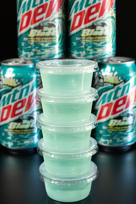 A stack of light blue Baja blast jello shots in front of cans of the soda. Margarita Jello Shots Tequila, Party Jello Shots, Best Margarita Jello Shots, Baja Blast Alcohol Drink Recipes, Camping Jello Shots, Vodka Jello Shots Easy, Jello Shots Rum, Mixed Soda Recipes, Margarita Jell-o Shots