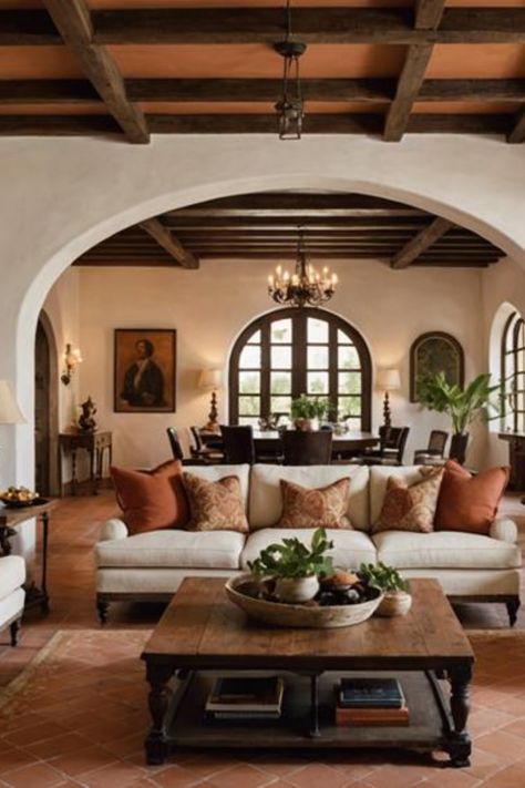 Cozy living room with white sofas and orange pillows, wooden coffee table, arched doorways, and exposed wooden beams on the ceiling. Roman Interior Design Style, Spanish Style Interior Design Living Room, Spanish Colonial Office, Spanish Hacienda Living Room, Spanish Eclectic Interior, Mediterranean Homes Living Room, Traditional Home Interiors Living Room, Spanish Home Aesthetic, Spanish Inspired Living Room