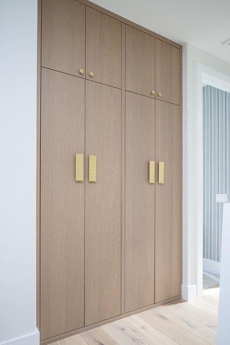 Brass hexagon hardware complements stacked floor-to-ceiling brown oak hallway cabinets. Hallway Storage Ideas, Oak Hallway, Hallway Cabinets, White Beveled Subway Tile, Hallway Storage Cabinet, Floor To Ceiling Cabinets, Hall Cabinet, Hallway Cabinet, Hallway Flooring