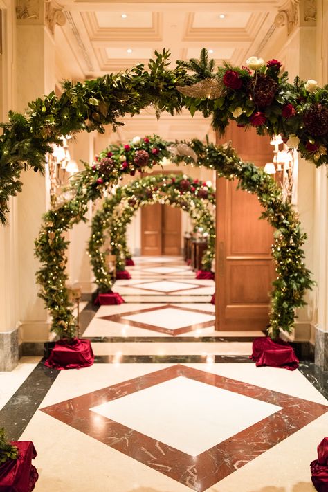 An extraordinary christmas wedding aisle adorned with lots of arches, which are decorated with red flowers, golden christmas garland and christmas lights Christmas Wedding Stage Decorations, Christmas Aisle Decorations, Christmas Floral Arch, Christmas Decor Hotel, Christmas Wedding Aisle, Christmas Garland Arch, Christmas Wedding Arch, Christmas Wedding Ideas Elegant, Christmas Arches