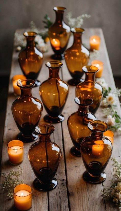 Amber glass vases add a touch of warmth and sophistication to barn weddings. I love how they create a cozy glow when filled with candles or fairy lights. Amber Glass Bottles Decor, Amber Jars Wedding, Amber Glass Wedding Table, Amber Glassware Wedding, Amber Vases Wedding Centerpieces, Amber Color Aesthetic, Amber Glass Wedding, Cozy Fall Wedding, 2026 Wedding