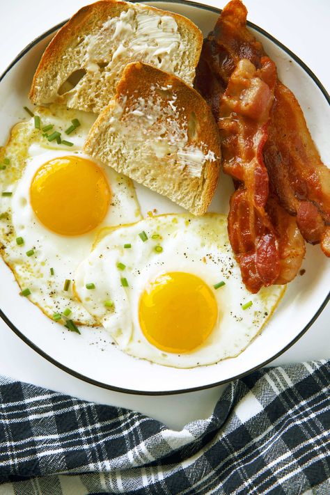 An overhead view of two Sunny Side Up Eggs on a plate with bacon and buttered toast. A plaid dish towel is laying next to it. Sunny Side Up Eggs Recipe, Boneless Prime Rib Recipe, Jus Sauce, Prime Rib Au Jus, Sunny Side Up Eggs, Gf Cookies, Buttered Toast, Prime Rib Recipe, Carnitas Recipe