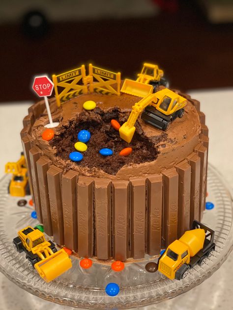 Chocolate digger cake surrounded by Kit Kat’s and M&Ms Tonka Truck Birthday Party Cake, Diggers Birthday Cake, Digger Themed Birthday Cake, Construction Worker Birthday Cake, Construction Dirt Cake, Chocolate Digger Birthday Cake, Construction Birthday Cake 4, Easy Construction Birthday Cake, Digger Cake Ideas