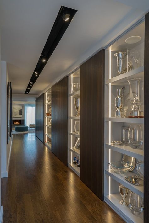 Illuminated modern shelving lines a hallway. Recessed vertical lighting and a recessed track light system in the ceiling create a contemporary display area. Modern interior design by Walker Architects. Awards Display Wall, Award Shelves, Trophy Display Shelves, Gallery Lights, Hallway Landing, Trophy Cabinets, Display Shelf Design, Display Cabinet Design, Trophy Display