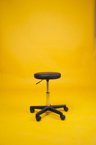 Black stool chair with wheels over an isolated yellow background. Chair Background For Editing, Background Design For Editing, Photo Studio Design Backgrounds, Job Background, Photo Studio Background Images, Watches Video, Photography Chair, Chair Background, Background Furniture