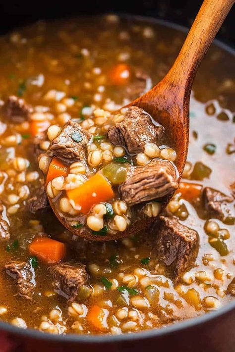 A close-up shot of a wooden spoon scooping beef barley soup from a pot. The soup is rich and thick with chunks of tender beef, whole barley grains, diced carrots, and finely chopped herbs, showcasing a hearty and nutritious meal. Stew Recipe Slow Cooker, Crockpot Beef Barley Soup, Beef And Barley Stew, Beef Barley Stew, Beef And Barley Soup, Barley Stew, Beef And Barley, Recipe Slow Cooker, Beef Barley