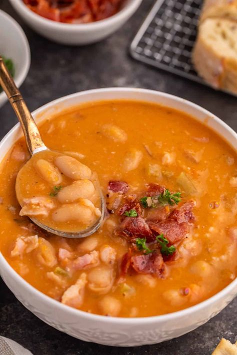 Bean with Bacon Soup Whip up a bowl of cozy, nostalgic Bean with Bacon Soup, made from simple ingredients that come together to create a hearty blend of creamy white beans and smoky bacon. This homemade, flavorful delight is easy to prepare and undoubtedly better than any canned version you've tasted before. White Bean Bacon Soup, White Bean Soup With Bacon, Creamy Bacon And White Bean Soup, Homemade Bean And Bacon Soup, Bean Bacon Soup Recipes, Bean And Bacon Soup For Canning, Soup With Bacon In It, Creamy Bean Soup With Kielbasa, Bean And Bacon Soup Recipe