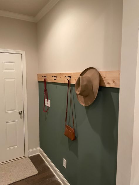 Green accent wall in entryway hallway/mud room with coat hangers and natural wood accent. Black White And Green Entryway, Boho Green Accent Wall, Sage Green Entryway Wall Colors, Mudroom Accent Wall Ideas, Green Wall Entryway, Green Accent Wall Hallway, Entrance Accent Wall Ideas, Green Mudroom Walls, Dark Green Entryway Walls