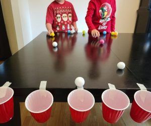 Family Minute to Win it Games for Christmas Parties 2021 | Happy Mom Hacks Easy Nye Games For Kids, Christmas Toss Game, Cup Pong Christmas Game, Christmas Team Games For Kids, Minute To Win It Cup Stacking, Minute To Win It Games With Ping Pong Balls, Red Solo Cup Party Games, Solo Cup Balloon Game, Christmas Games For Family With Ping Pong Balls