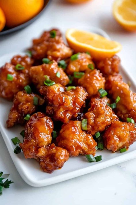 Slow Cooker Orange Chicken. A plate of crispy orange chicken bites, glazed with a sticky orange sauce, garnished with fresh scallions. A wedge of fresh orange sits in the background, adding a burst of color. Crockpot Recipes Orange Chicken, Slow Cooker Orange Chicken Recipes, Orange Chicken Crockpot Recipes, Crockpot Orange Chicken Recipe Easy, Easy Orange Chicken Crock Pot, Orange Chicken Recipe Crockpot, Orange Chicken Instant Pot, Orange Chicken Crockpot, Easy Crockpot Orange Chicken