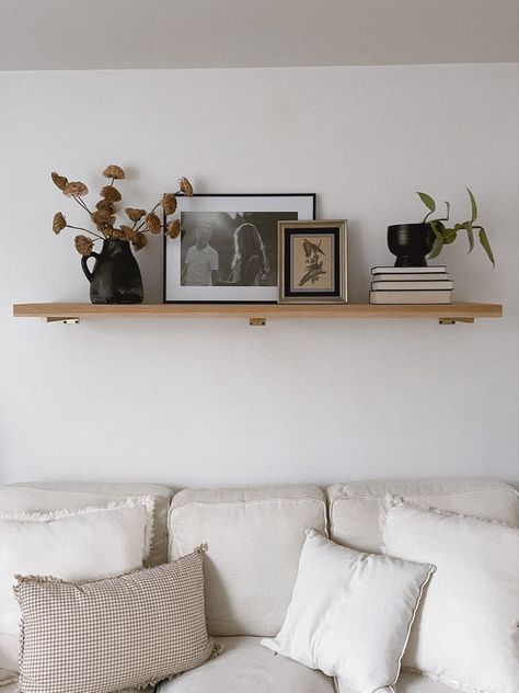 Large Living Room Shelf, Simple Living Room Shelf Decor, Floating Shelf Above Credenza, Floating Mantle Above Couch, Practical Shelf Styling, Floating Shelf Wall Sconces, Wood Shelf Over Bed, Single Shelf Styling Living Room, Two Shelves Above Couch