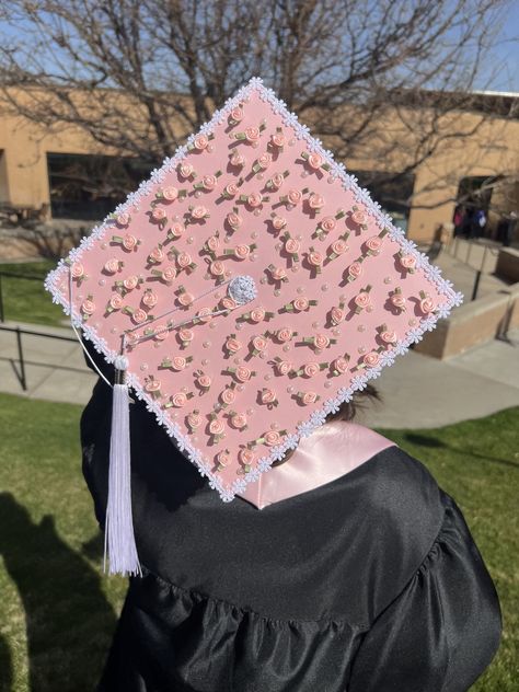 An SUU graduate facing away from the camera, so the top of their grad cap is visible. The grad cap decoration has a pink background, and is covered in many small pink roses. The perimeter of the cap is lined with a string of white daisies. Islamic Grad Cap Ideas, Grad Caps With Bows, Strawberry Graduation Cap, Pink Decorated Graduation Caps, Pink Cap Graduation, Pink Cap Decoration, Floral Grad Cap Designs, Graduation Cap Designs Coquette, Strawberry Grad Cap