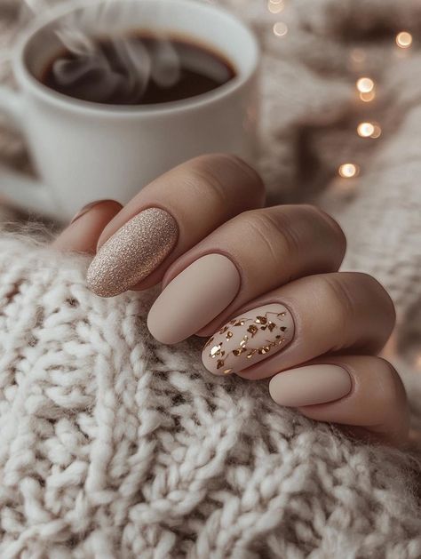 Dieses luxuriöse Design kombiniert eine matte Nude-Basis mit einem glitzernden Akzentnagel und einem Nagel mit goldenen Folienflocken. Die Mischung aus mattem Finish und schimmernden Details sorgt für einen eleganten und warmen Look, perfekt für den Winter.