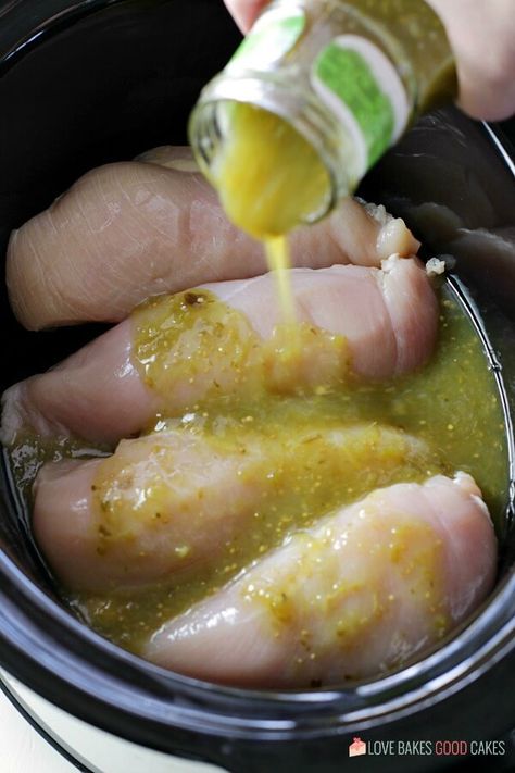 salsa verde being pored over chicken Salsa Verde Recipes Meals, Green Chicken Crockpot, Crockpot Chicken With Green Enchilada Sauce, Crockpot Chicken Verde Recipes, Salsa Verde Queso Crockpot Chicken, Salsa Verde Recipe Meals, Chicken Verde Crockpot, Chicken Verde Recipes, Verde Chicken Recipes