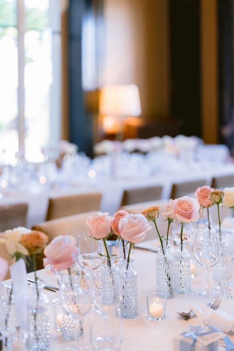 A wedding table centerpiece made of hundreds of bud vases, each cradling a rose in a palette of pale and blush pinks Bridal Shower Bud Vases, Simple Rose Table Centerpieces, Bud Vases Roses, Pink Bud Vase Centerpiece, Bud Vases With Roses, Wedding Table Centerpieces Vases, Pink Bud Vases Wedding, Rose Bud Vase Centerpiece, Single Rose Bud Vase Centerpieces