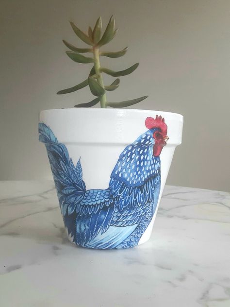 Blue rooster clay pot. This is a clay pot that has been painted white, and the design is a decoupage technique. This striking blue rooster is on one side of the pot. The pot measure 5.5-inch height by 6 inch diameter(top), with a drainage hole.  Please use a plastic liner inside of the pot if planting a live plant and keep the pot indoors to protect the design.  Lovely pot for a farmhouse decor theme, or any country style home! *Plant not included. Flower Pot Art, Terra Cotta Pot Crafts, Painted Clay Pots, Painted Terra Cotta Pots, Flower Pot Crafts, Bf Gifts, Decorated Flower Pots, Painted Flower Pots, Clay Pot Crafts