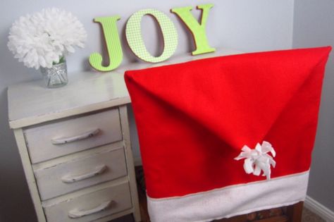 Spice up your dining room decor this season with homemade santa hat chair covers. Sew together these easy holiday decorations with felt and thread. Diy Santa Hat, Fabric Kitchen Chairs, Christmas Headbands, Christmas Sofa, Kitchen Chair Covers, Christmas Chair Covers, Chair Back Covers, Christmas Chair, Dining Room Chair Covers