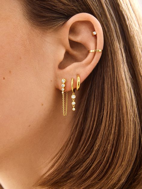 Introducing our Jenelle 18k Gold Earring Set – three times the charm in one stylish set. Choose between dainty drop earrings, delicate huggies with a shimmering drop accent, and a timeless huggie. Wear them all together or mix and match depending on your everyday mood. Either way, you’re set for years of style, thanks to its 18K gold plated sterling silver and Cubic Zirconia stones. Stack Hoop Earrings, Stack Earring Ideas, Ear Piercings Gold Jewelry, Cute Stacked Earrings, Gold Hoops Triple Piercing, Multi Piercing Earrings, Earring Inspiration Gold, 3 Earring Set, Opal And Gold Earrings